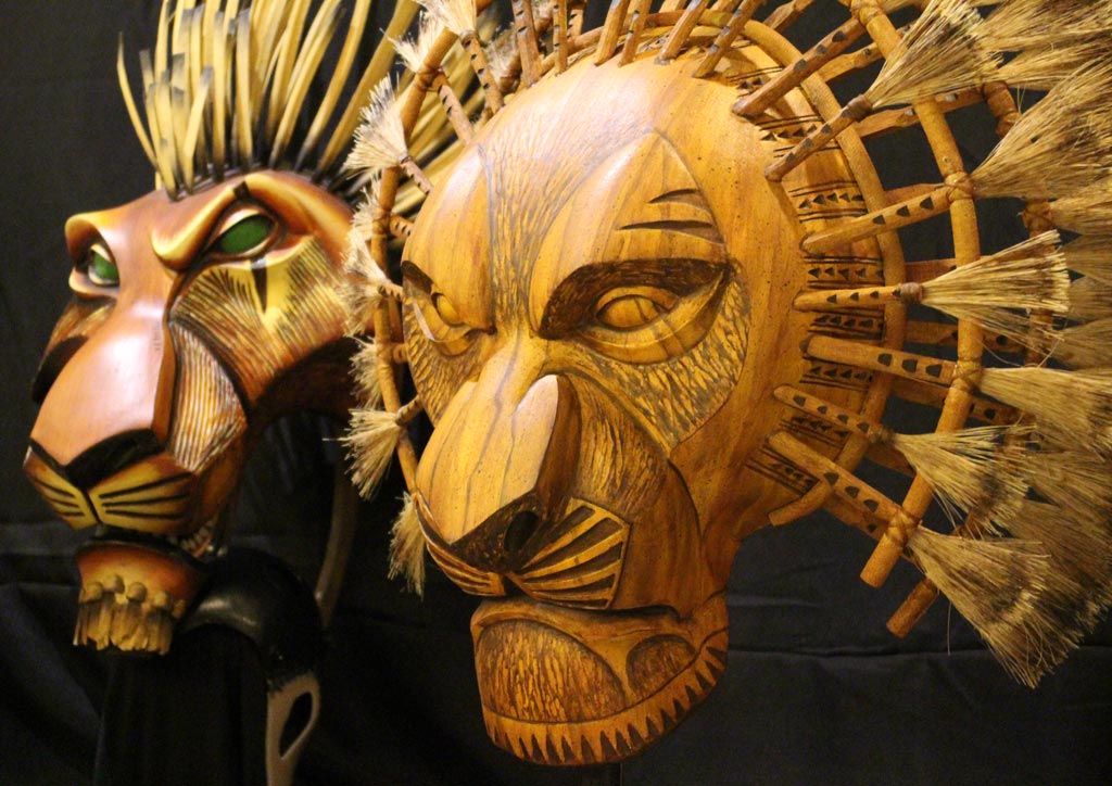 A close up view of the Scar and Mufasa masks. Both evoke the hard-crafted qualities of African wooden masks, but are made of lightweight carbon fiber. | Photo by Angel Yulo