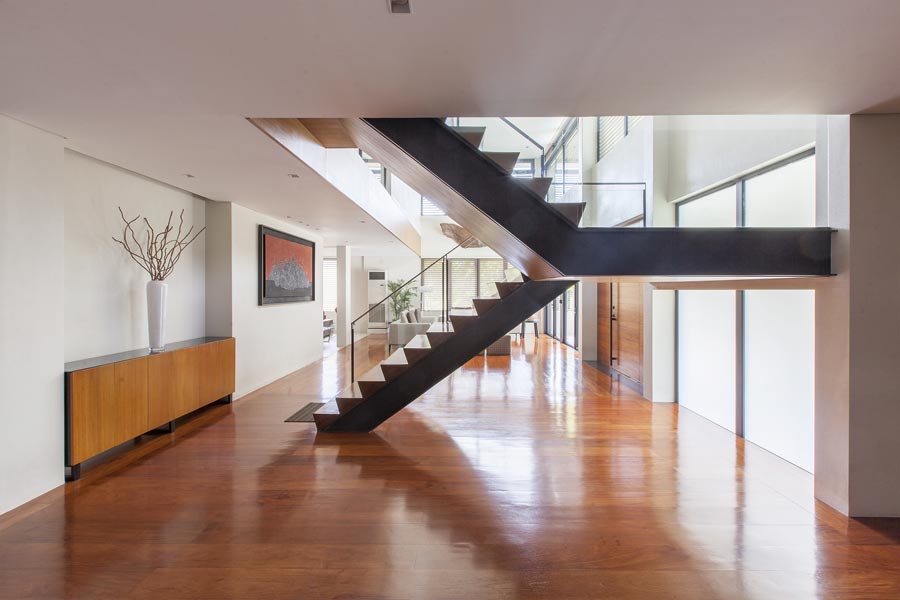 a stair case within a modern two storey house design with wooden floors and open plan concept.
