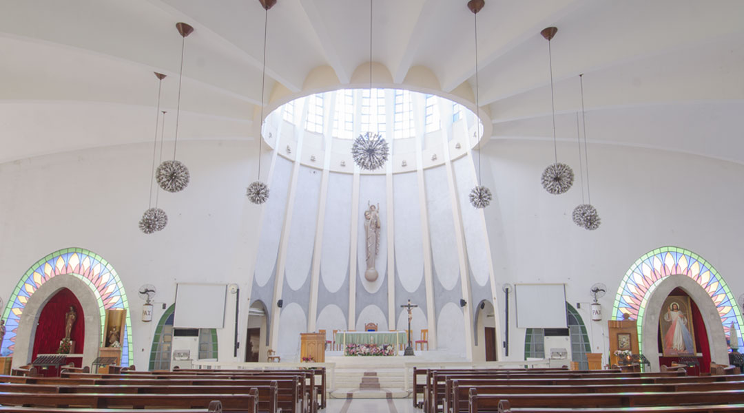 Natural light from the dome above the altar illuminates the church. The wooden statue of the Queen of Peace was created by Maximo Vicente, who is famous in the country for his carvings of religious iconography.