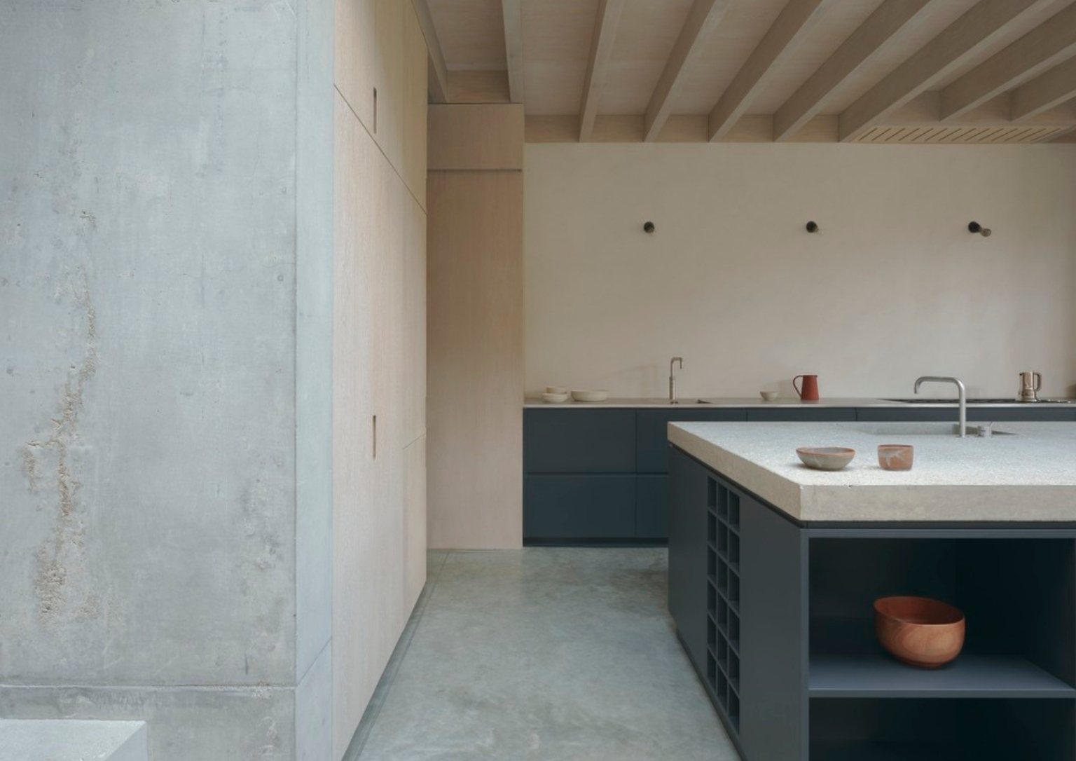 view of concrete kitchen island with sink and dark blue cabinetry