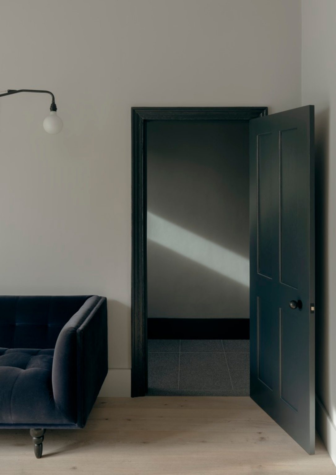 a dark open door next to a grey sofa