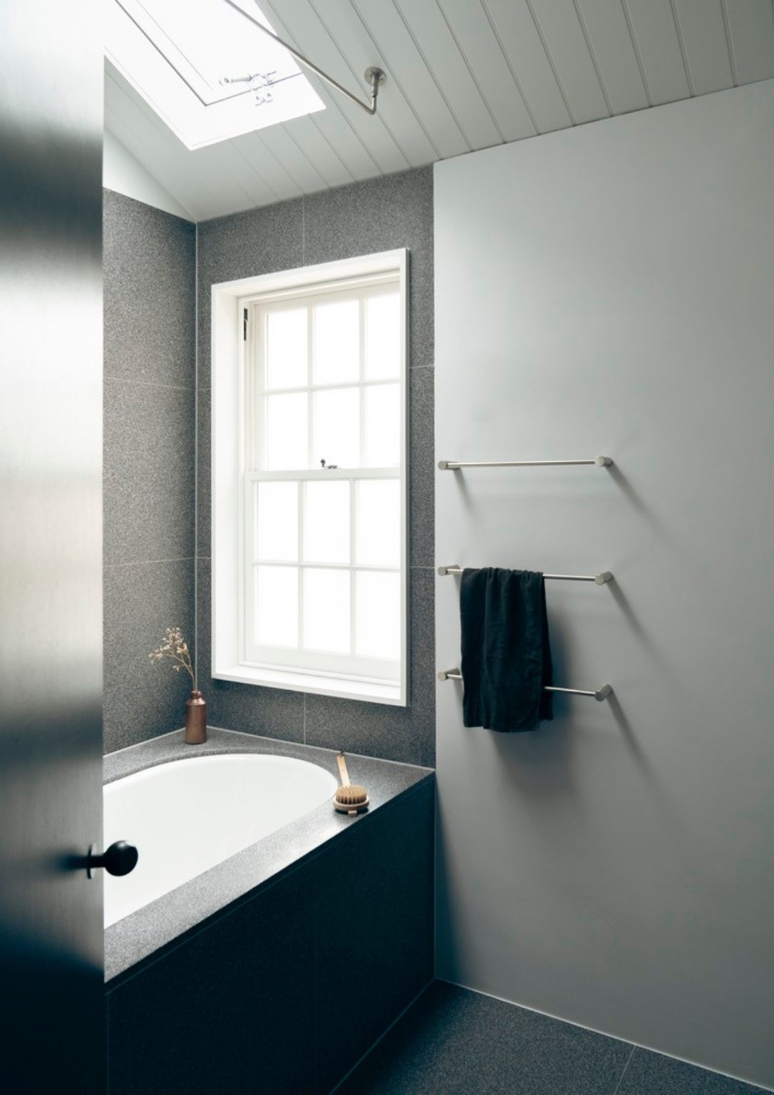 view of a minimalist bathroom with a deep bath tub under a skylight 