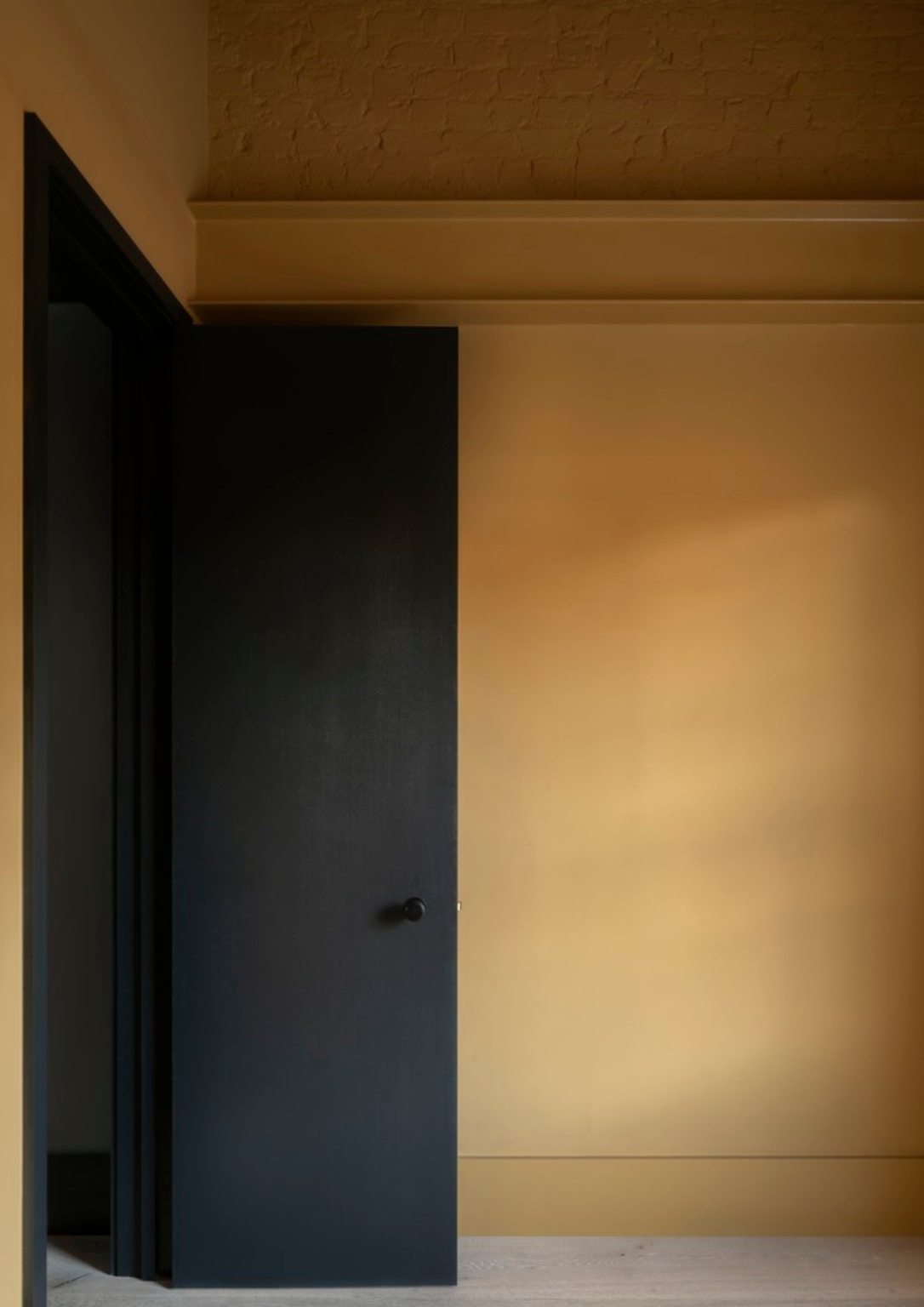 a dark open door against and orange wall
