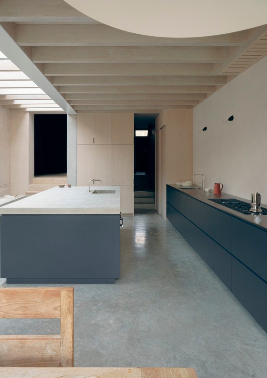 view of modern kitchen island and counter with dark blue lower cabinets and light wood joinery