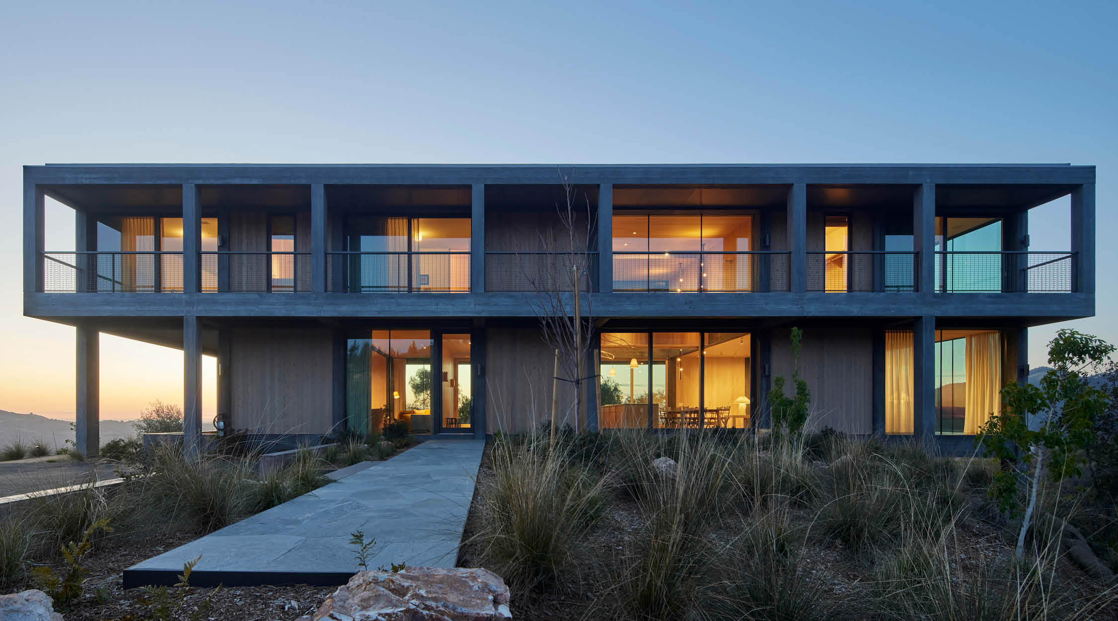 A modern two storey house design made of concrete and wooden accents featuring a grid system.
