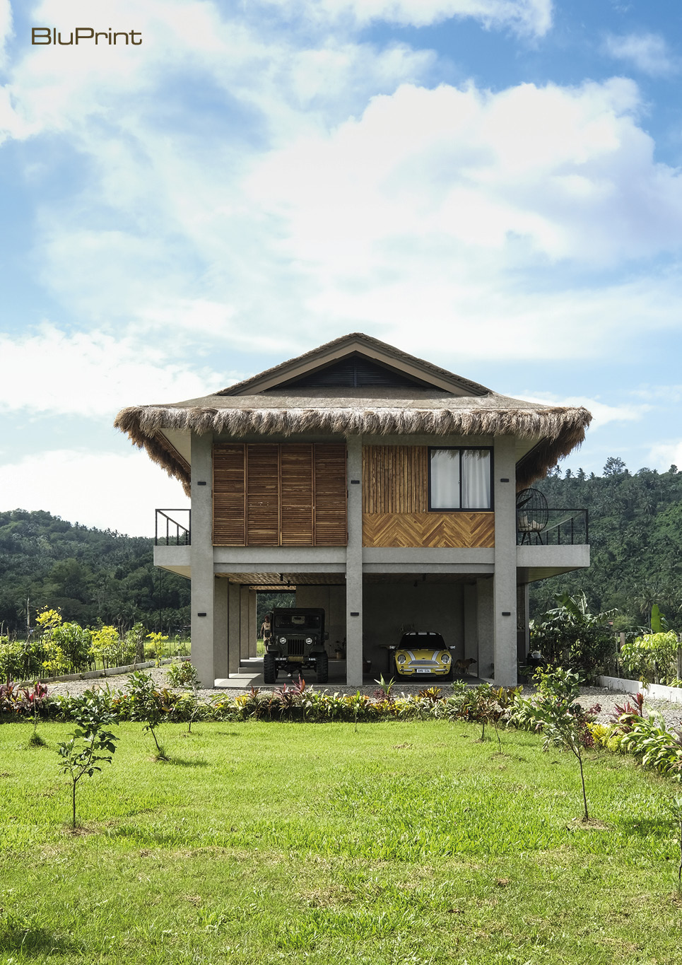 A side view of a modern bahay kubo on concrete stilts with a thatched roof.
