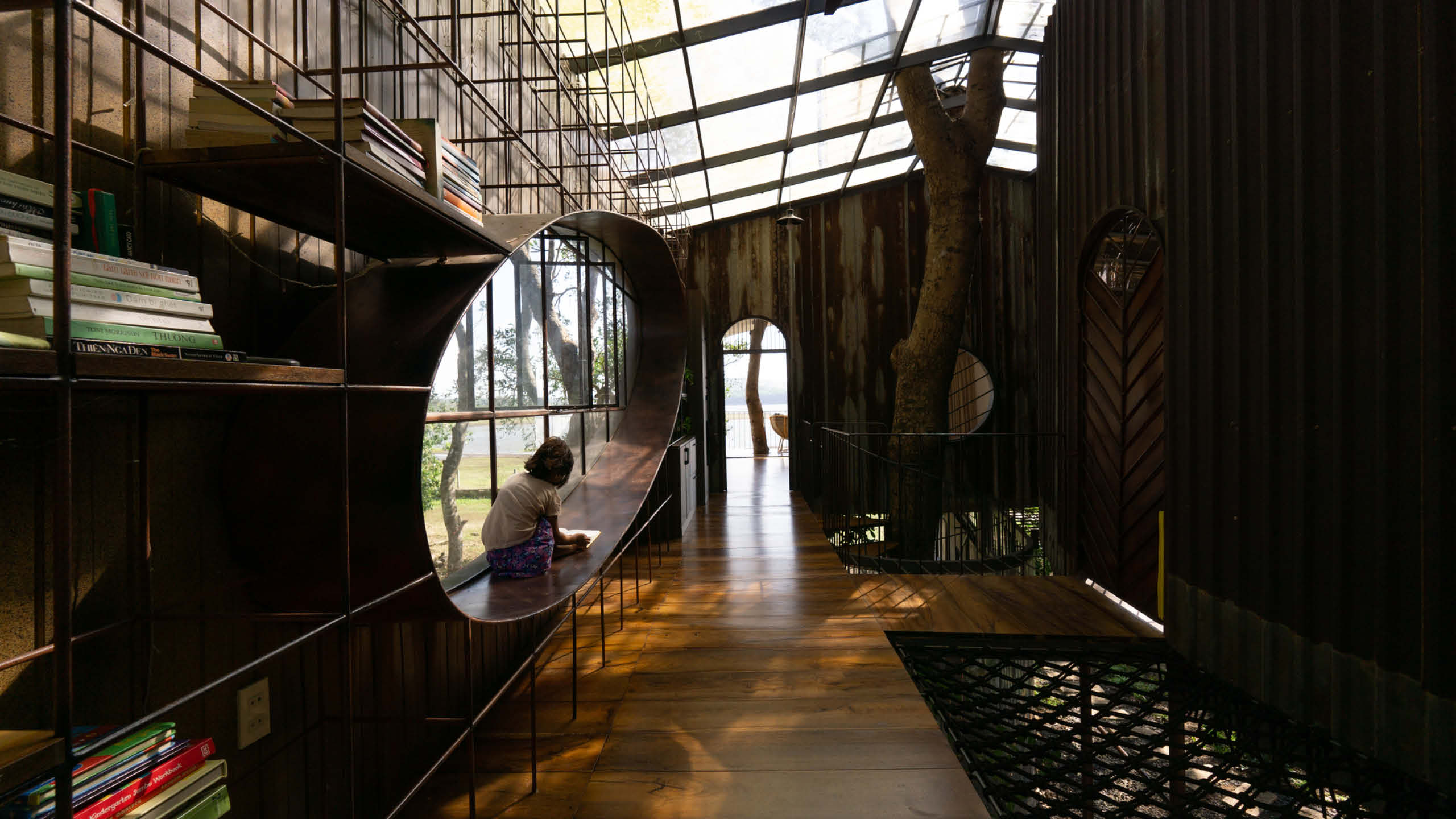 A child reads next to a large oblong window in a tree house.
