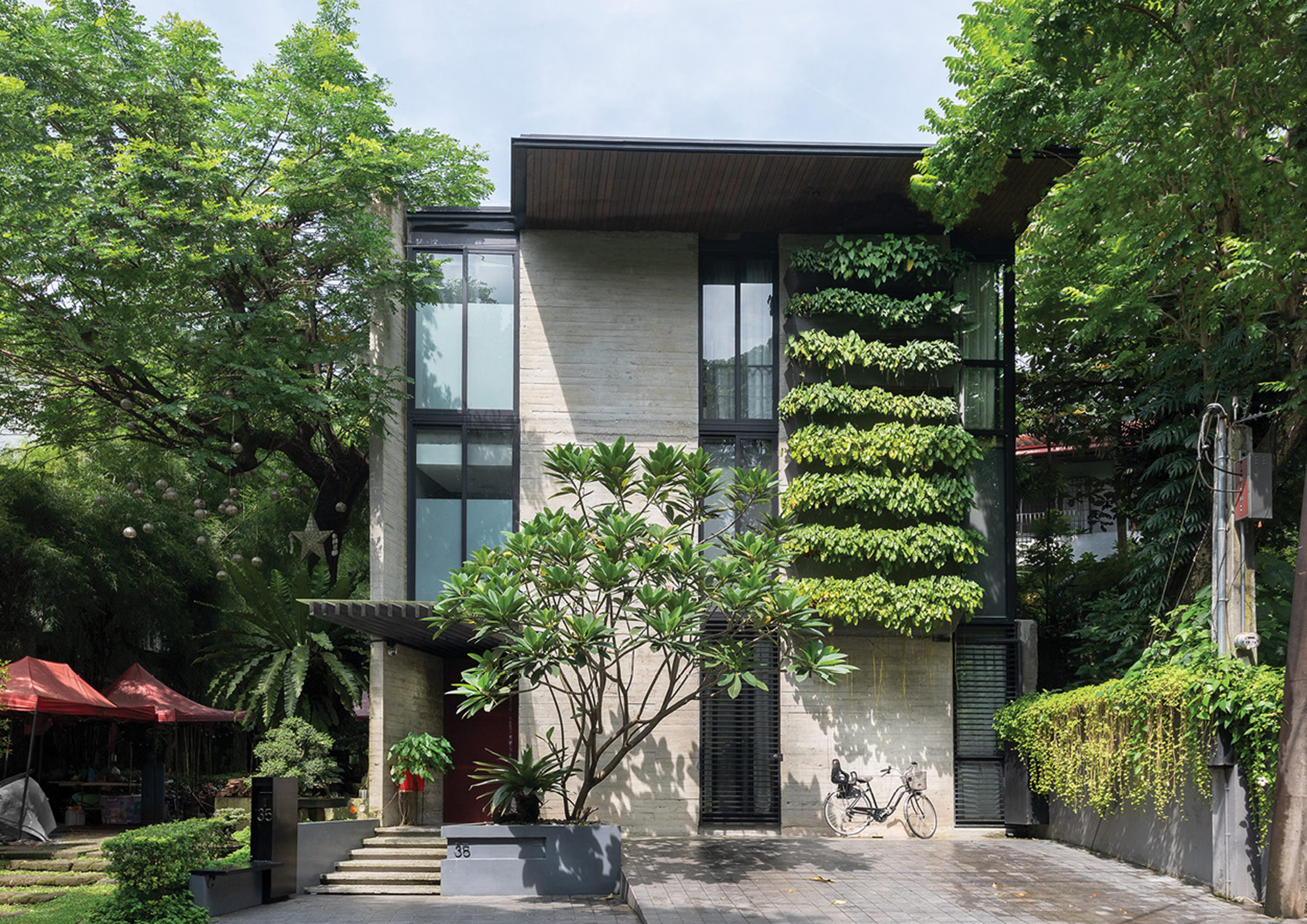 A narrow two storey concrete home with green wall designed by Sudar Khadka.