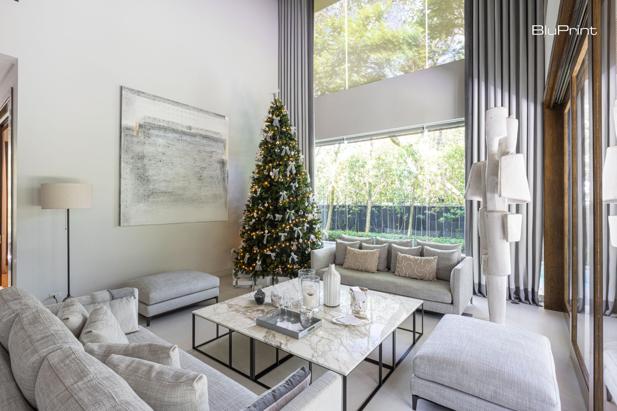 A four-meter Christmas tree dominates the home's living room featuring minimalist modern furniture.