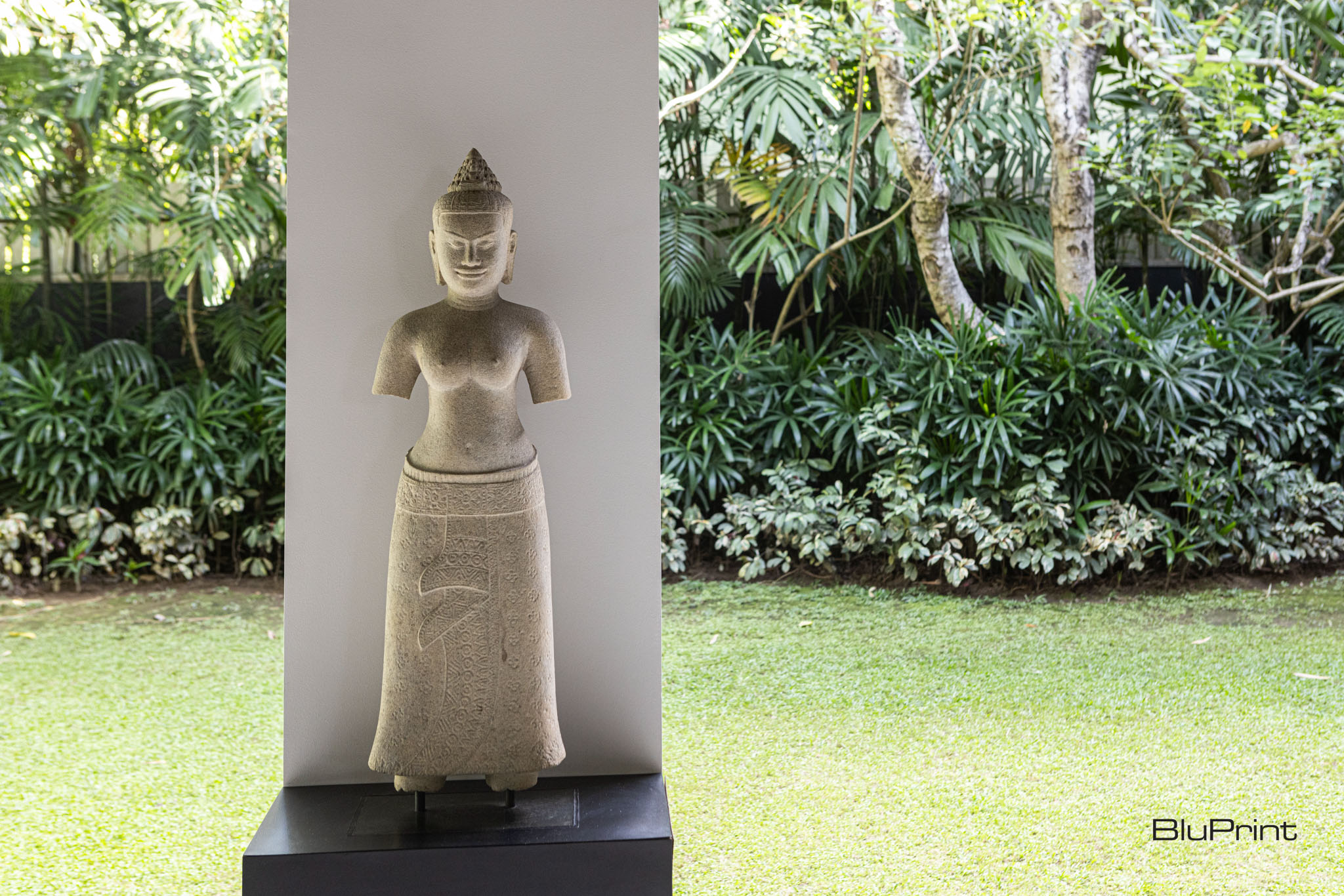 Buddhist statue against a column by the garden
