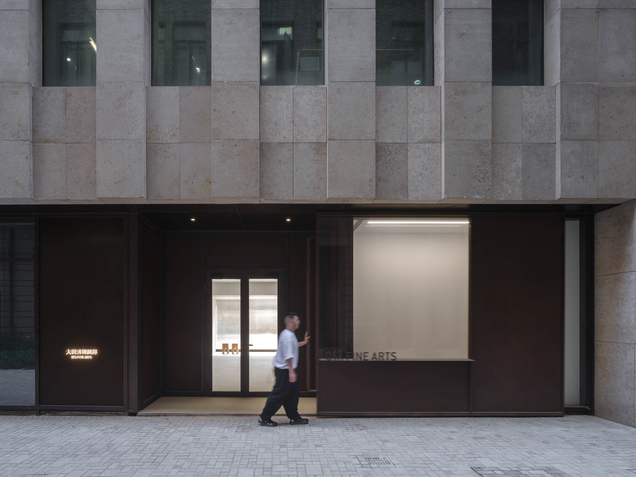 A man opens a large aged-metal sliding door to the gallery's entrance