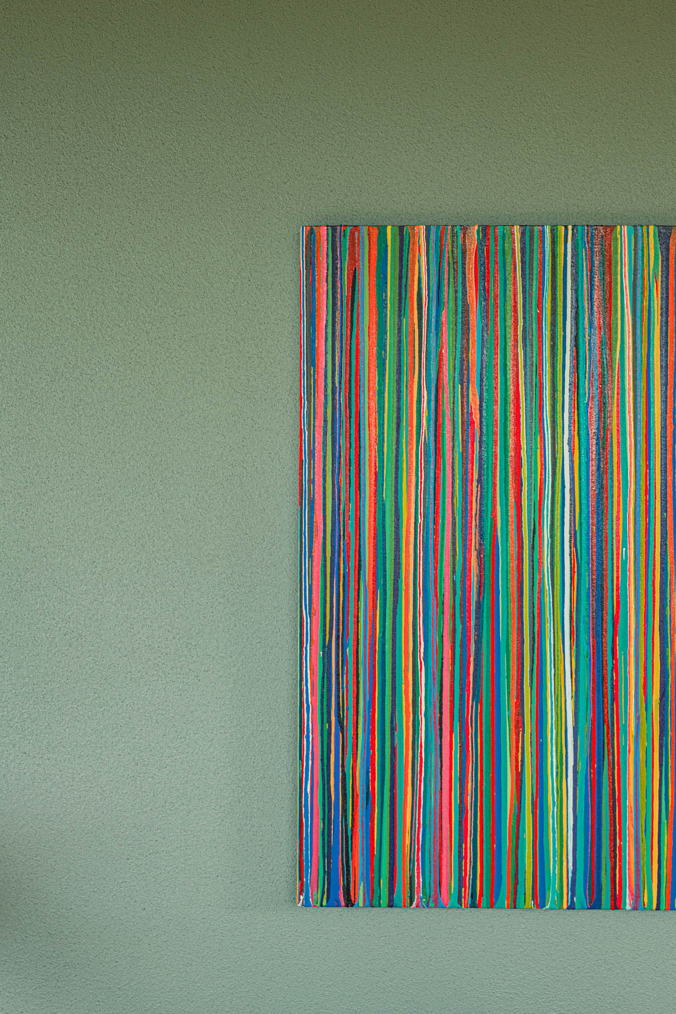 Abstract art hanging on a teal wall.
