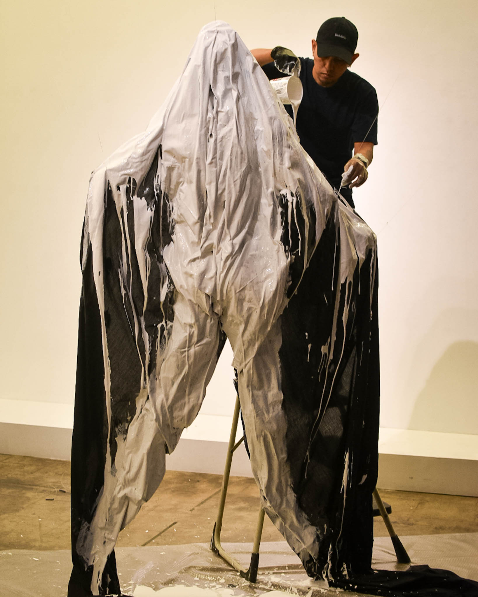 Artist Jayson Cortez preparing his sculptural piece of a figure draped in fabric