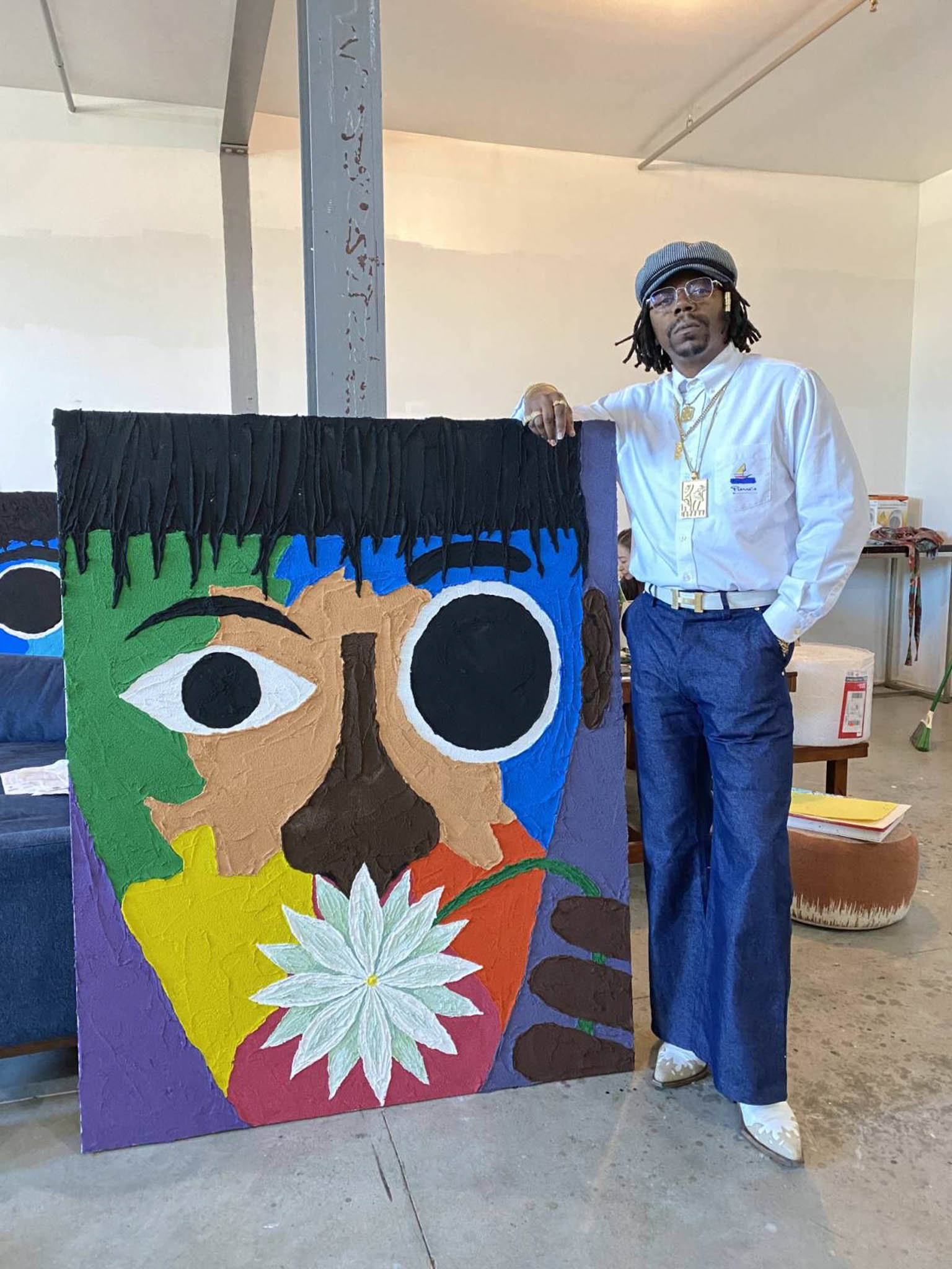 An artist stands beside his colorful work of art of an expressionist portrait.