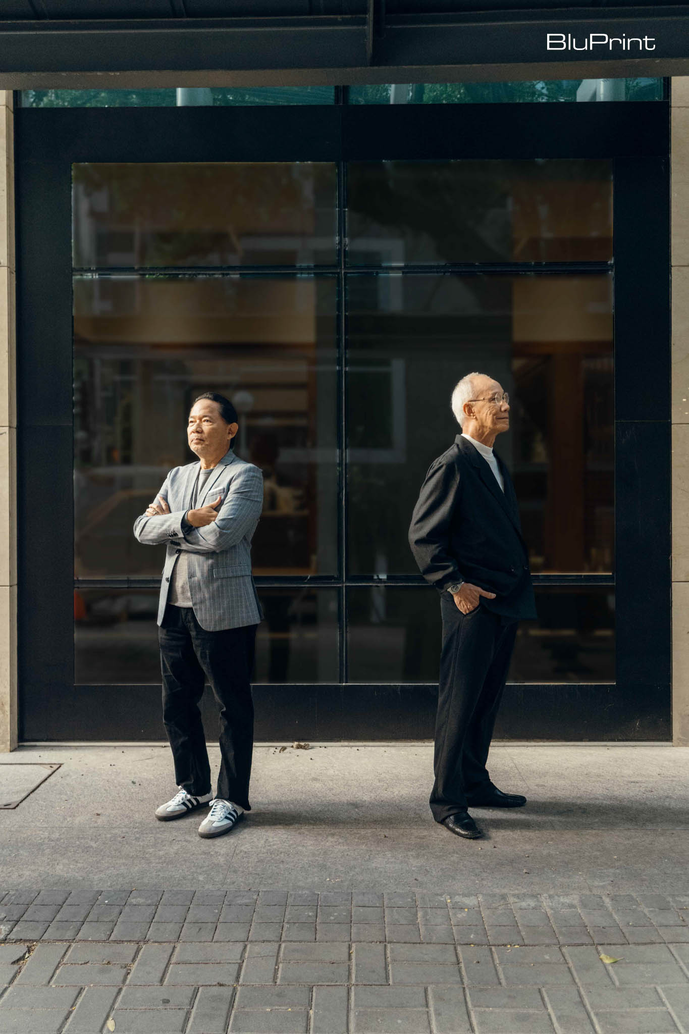 portrait of Meloy Casas and Bong Recio in suits in front of a glass facade