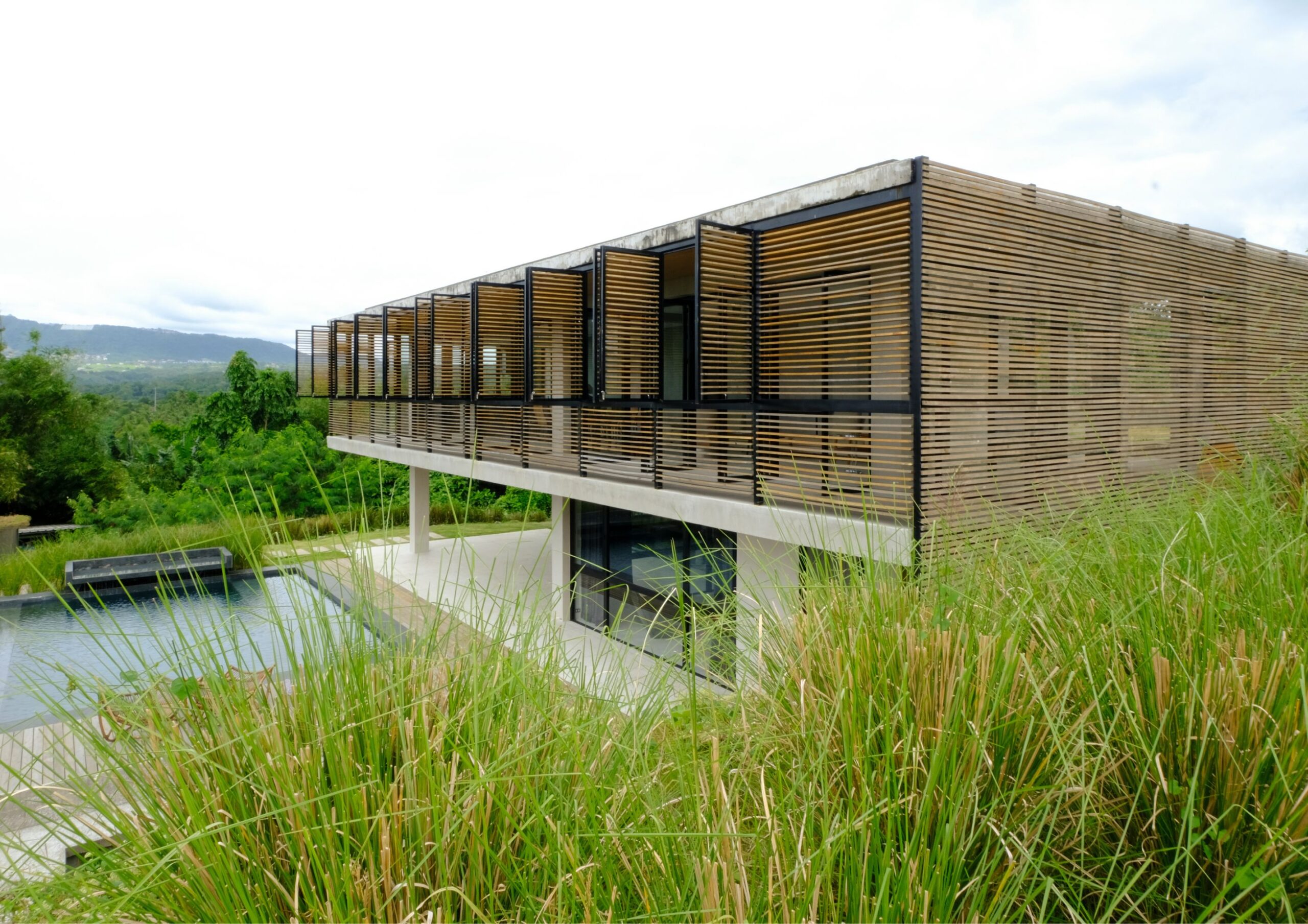 A 2 story concrete villa with wooden slats and a pool at Parallel in Tanauan, Batangas.