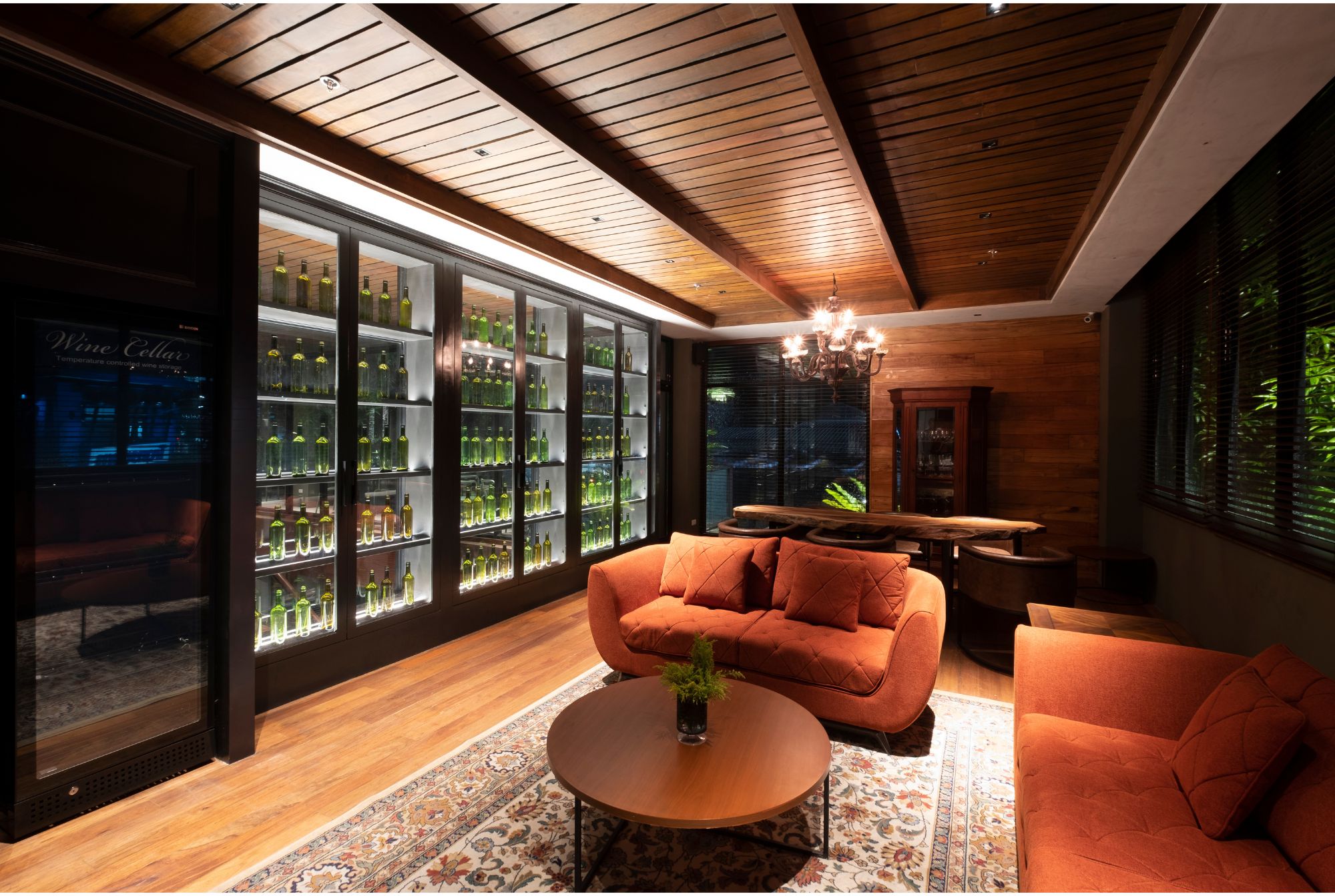 Cafe Bobs wine cellar with terracota colored seating, ornate rug, and large glass display case filled with wine bottles.