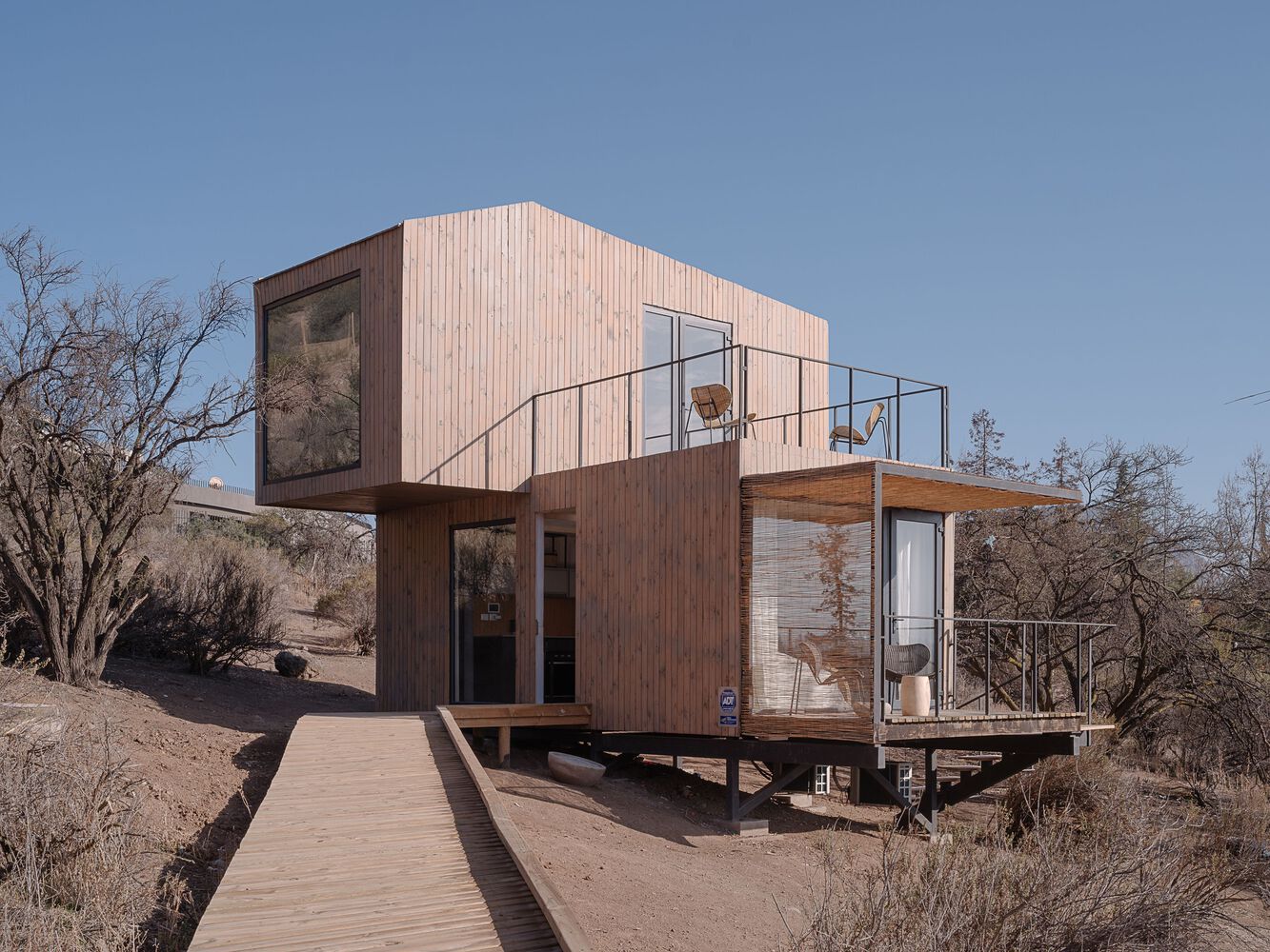 a two story sculptural wooden cabin with a modern tiny house design.