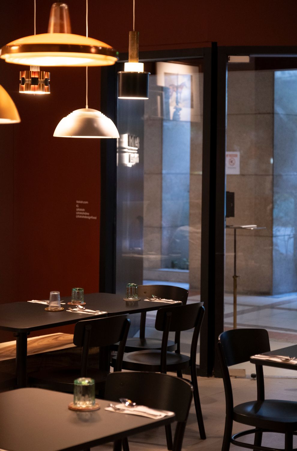 The minimalist dining area of Ito Kish Design Food with burgundy walls and vintage light fixtures.