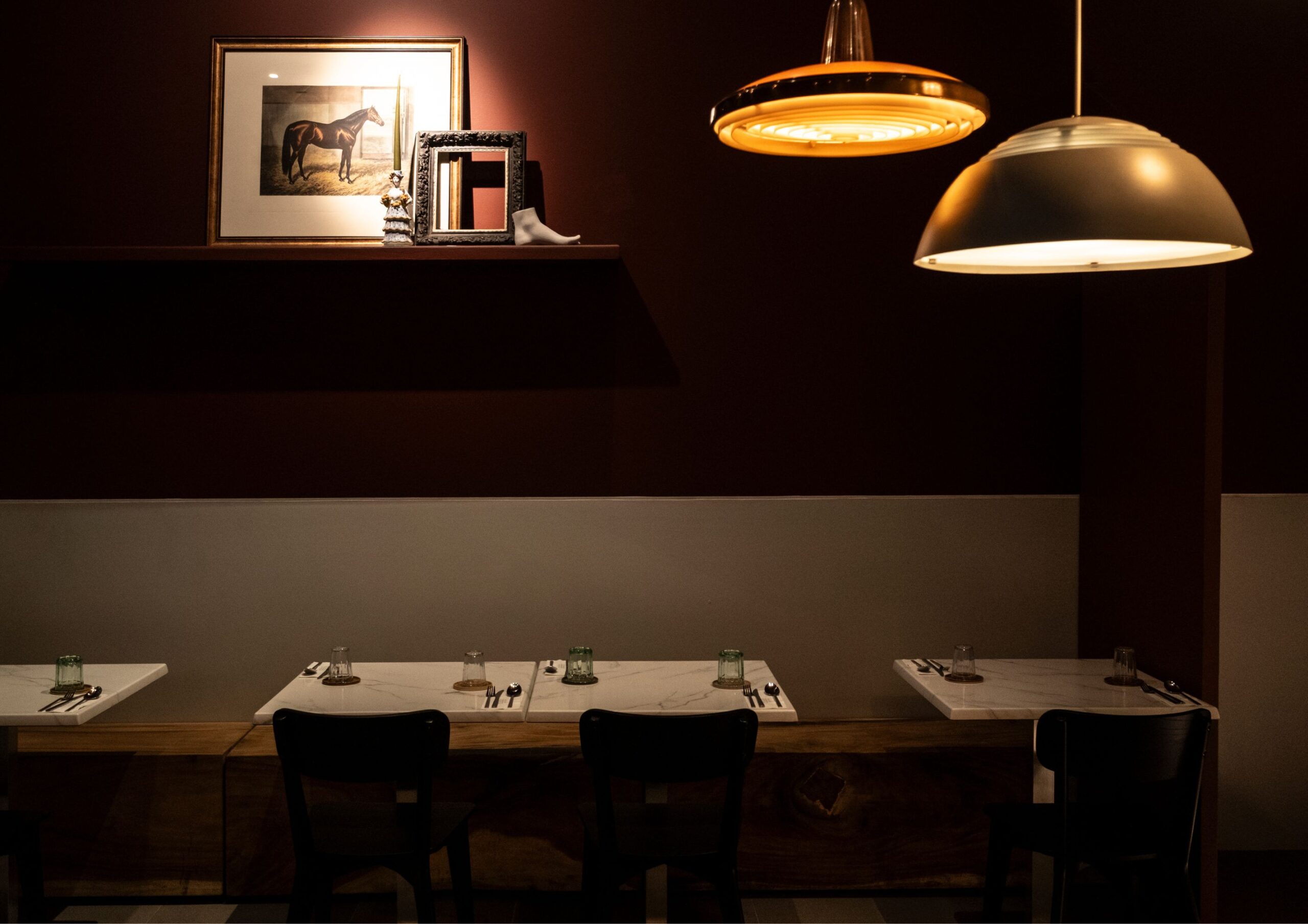 The minimalist dining area of Ito Kish Design Food with burgundy walls and vintage light fixtures.