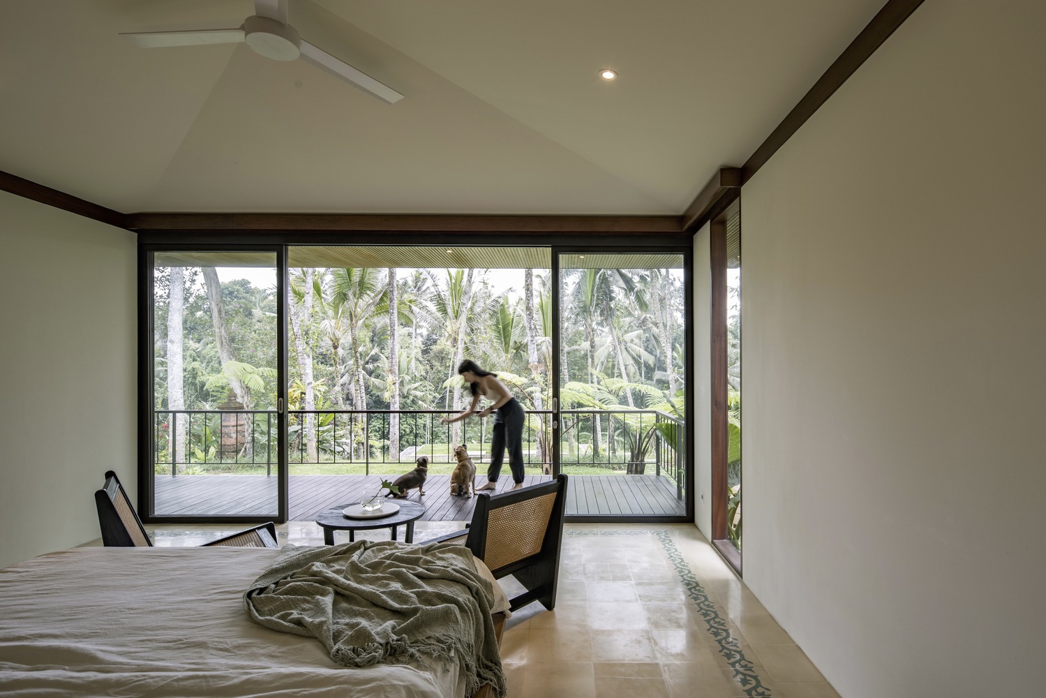 A bedroom that opens into a large balcony where a woman plays with her two dogs. Photo by Indra Wiras.