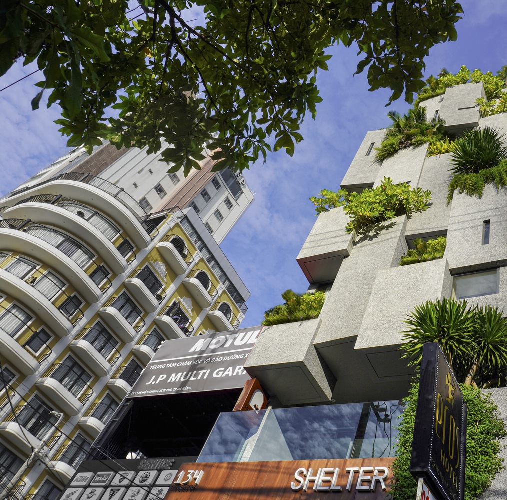 Shelter Stay's brutalist facade overflowing with tropical greenery.