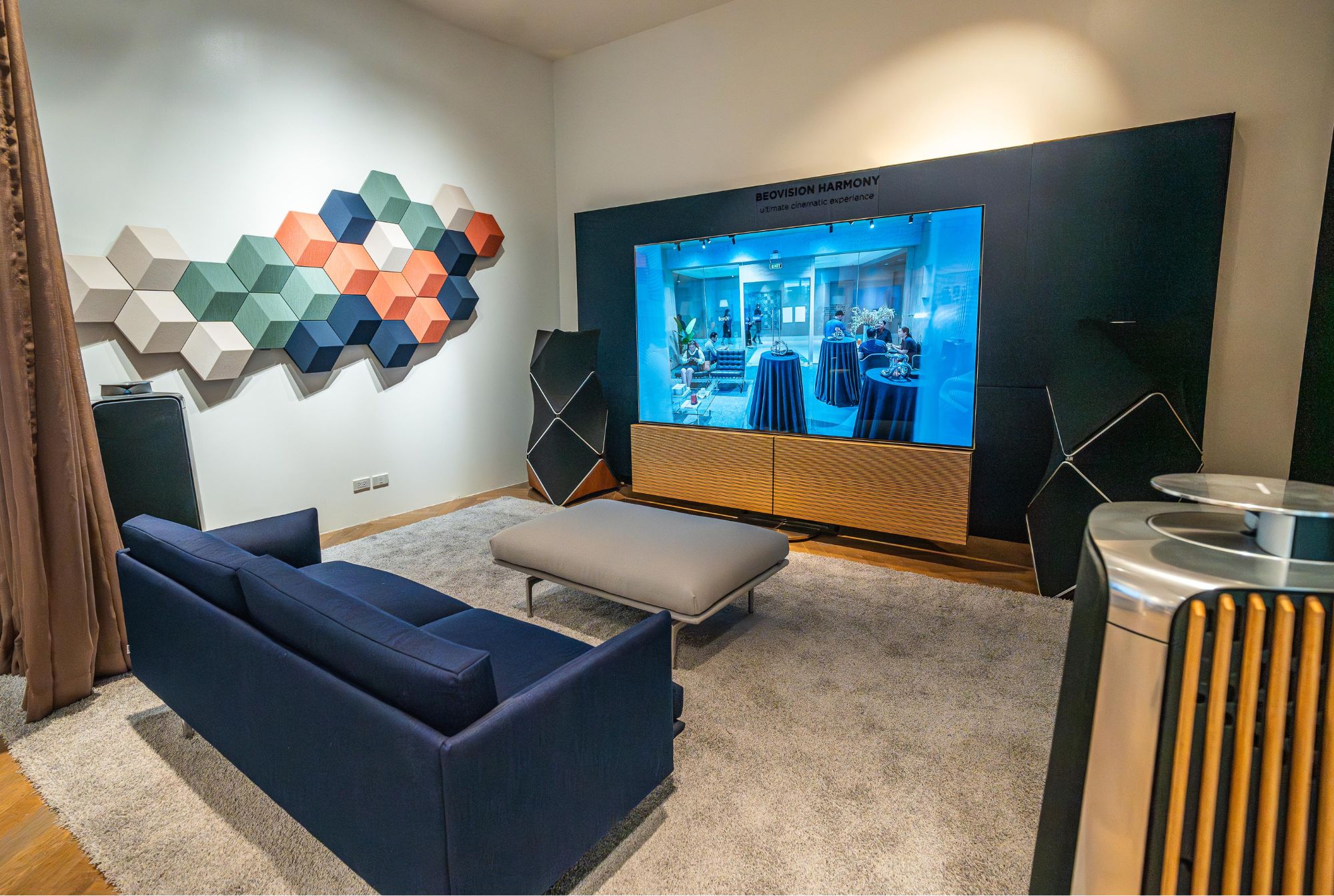 The Beovision Harmony boasts a 97 inch screen for a truly immersive cinematic experience. On the left are the Beosound speaker tiles, which also double as sound dampening.