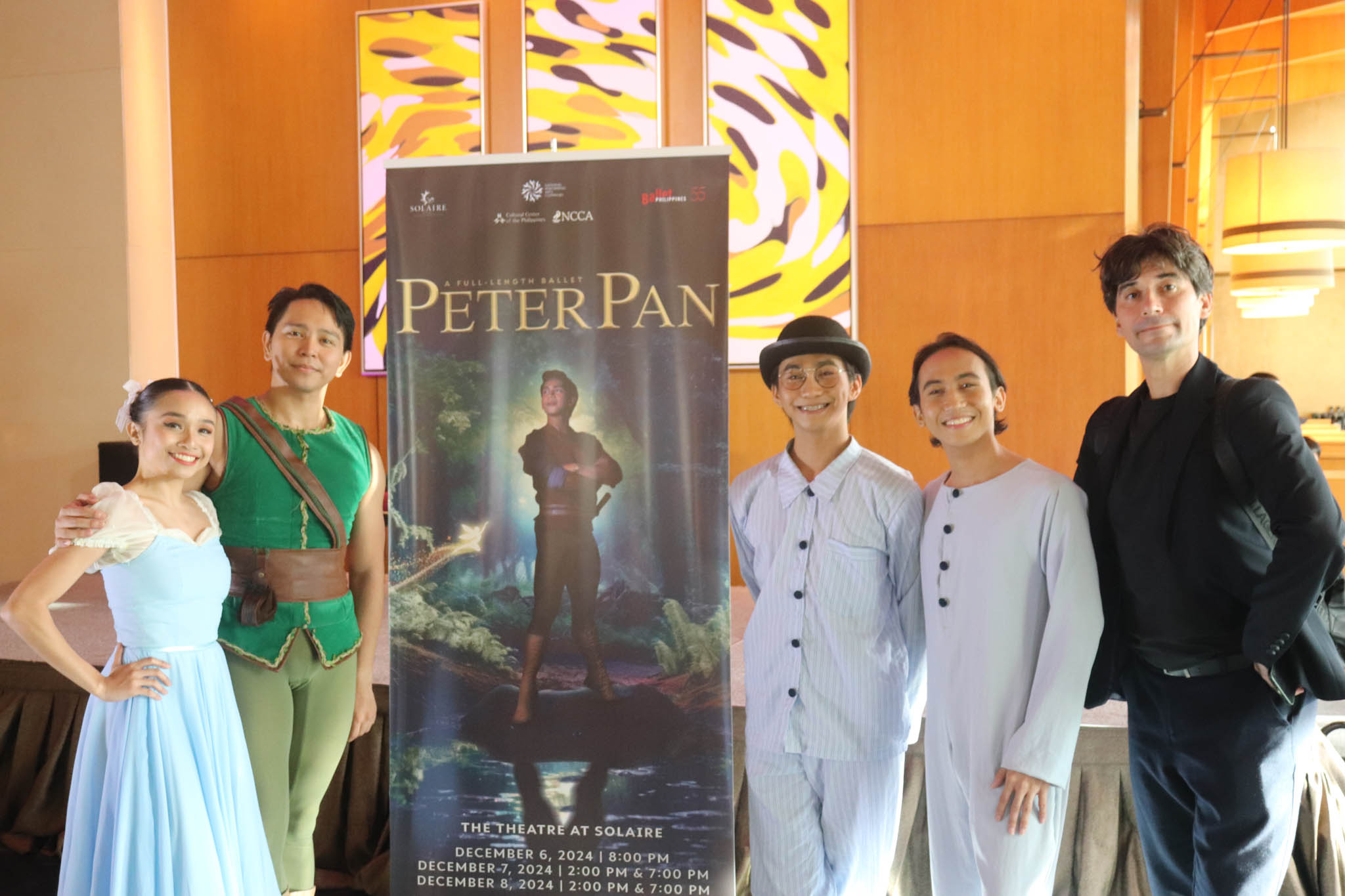 Ballet Philippines' artistic director and dancers posing beside the Peter Pan poster.