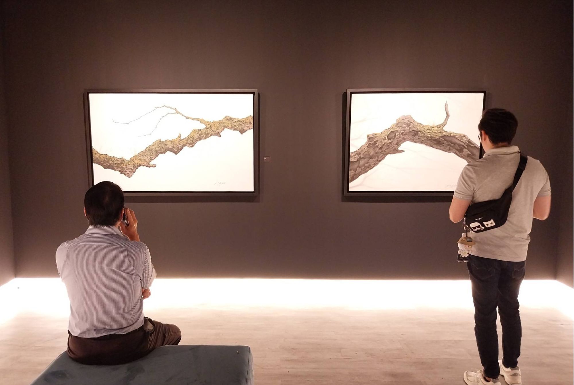 Two people looking at the paintings of "Echoes of Verdure."