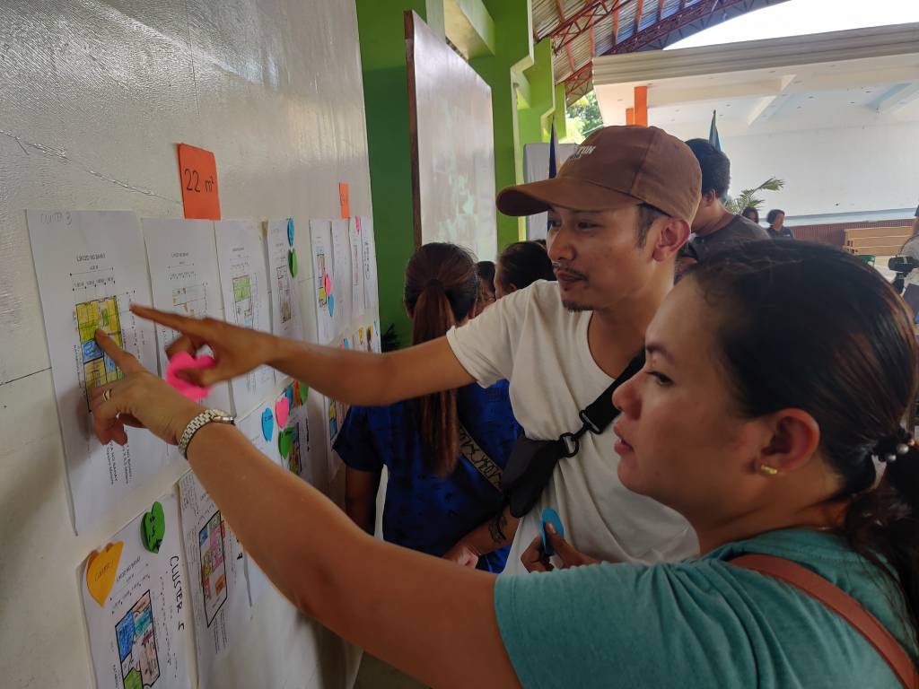 Members of the community analyzing some draft designs from workshops by Habitat for Humanity Philippines.