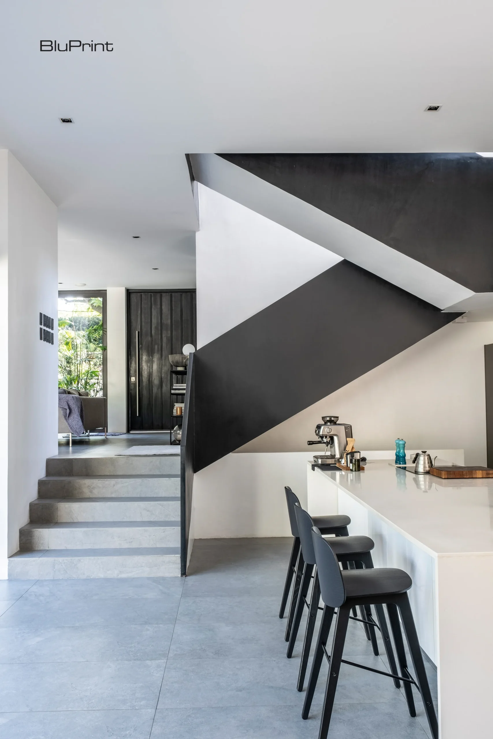 The kitchen of Descending House drops down with the land, following the site’s natural slope. A mirrored wall conceals storage, while a long counter makes it feel open and uncluttered.