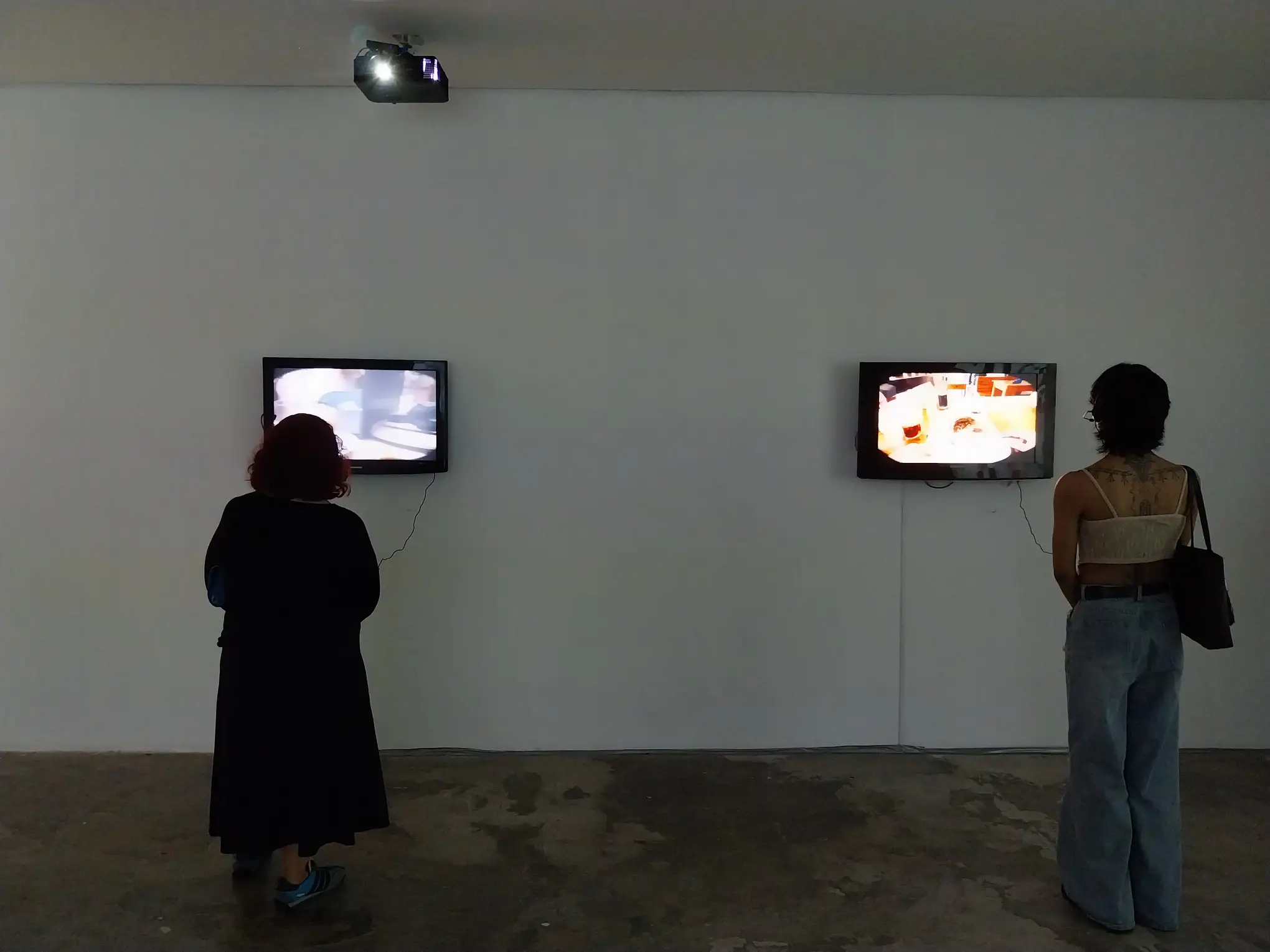 Gallery visitors watching "Sit in My Retina" by Lee Paje.