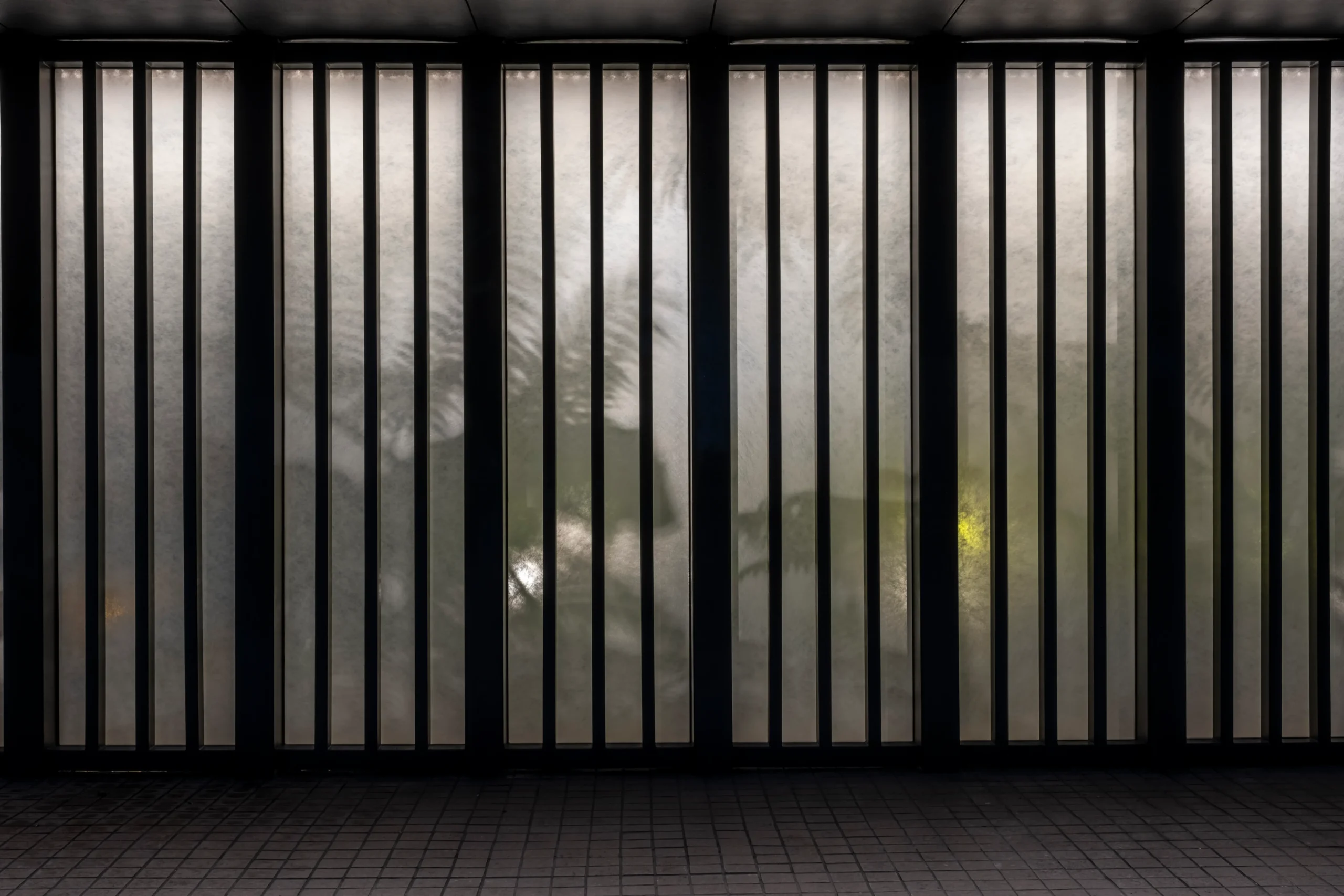 Translucent glass panels in between black steel bars. 