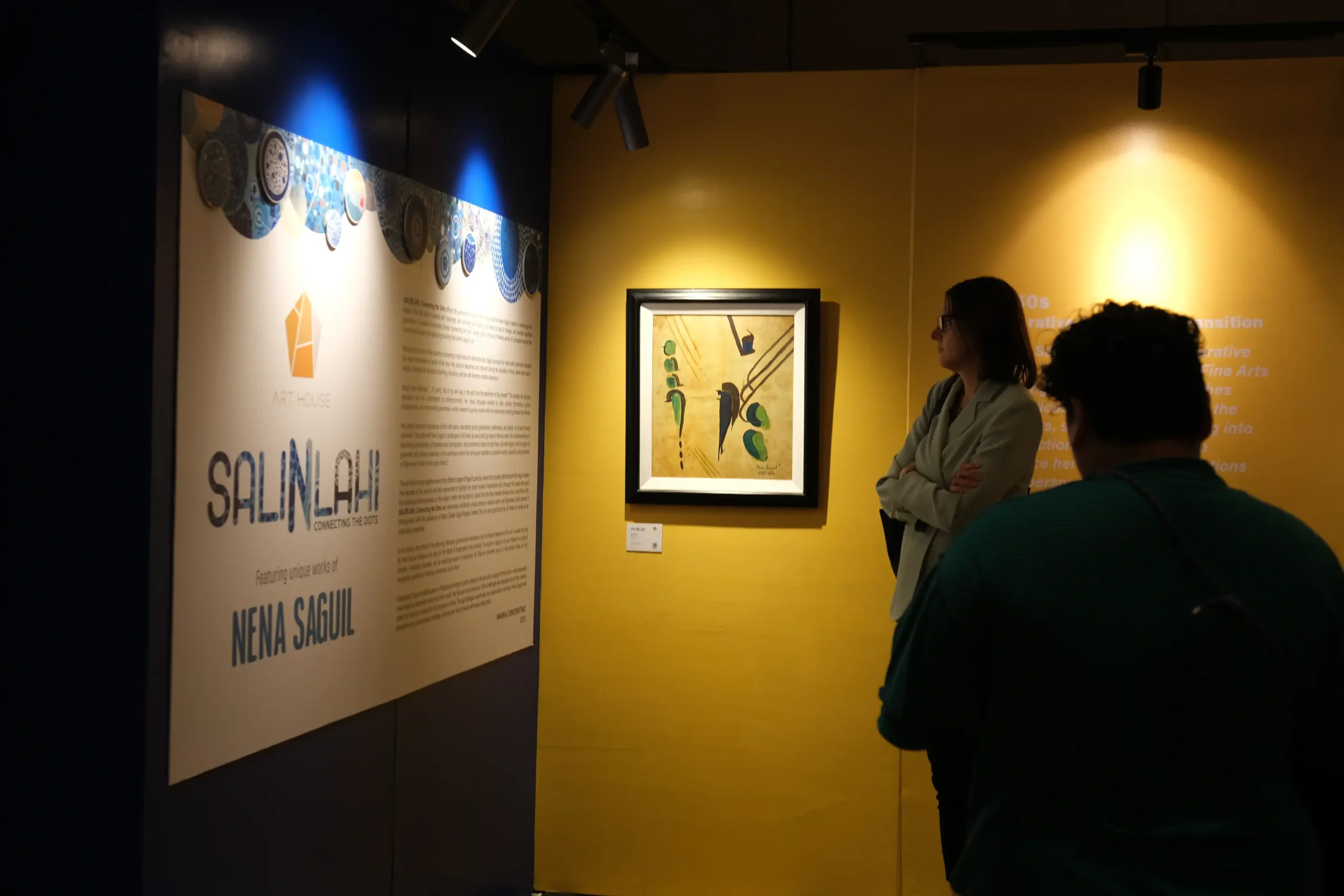 Visitors reading the write-up for the Nena Saguil exhibit "Salinlahi."