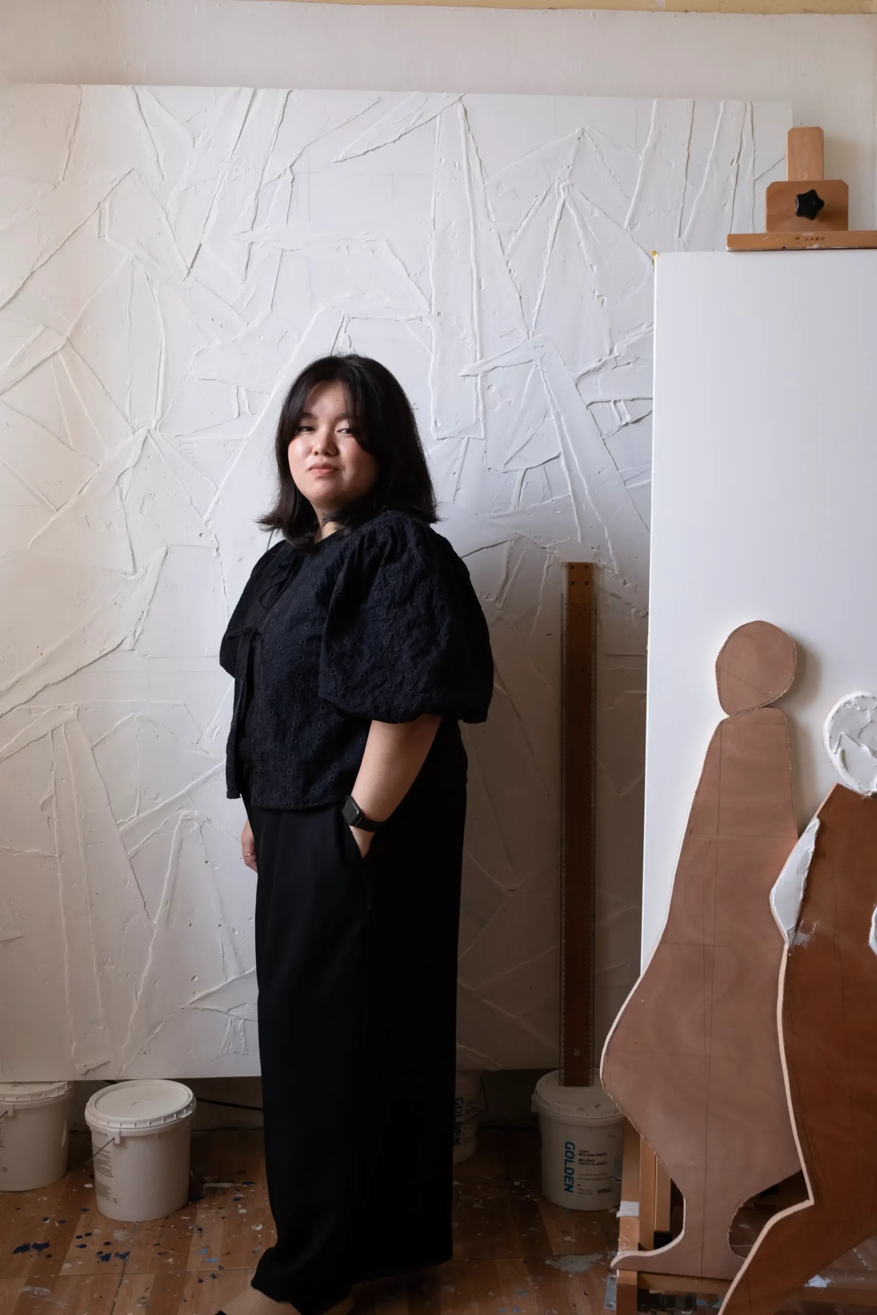 Thea Quiachon posing in front of a work-in-progress and other materials in her workshop.