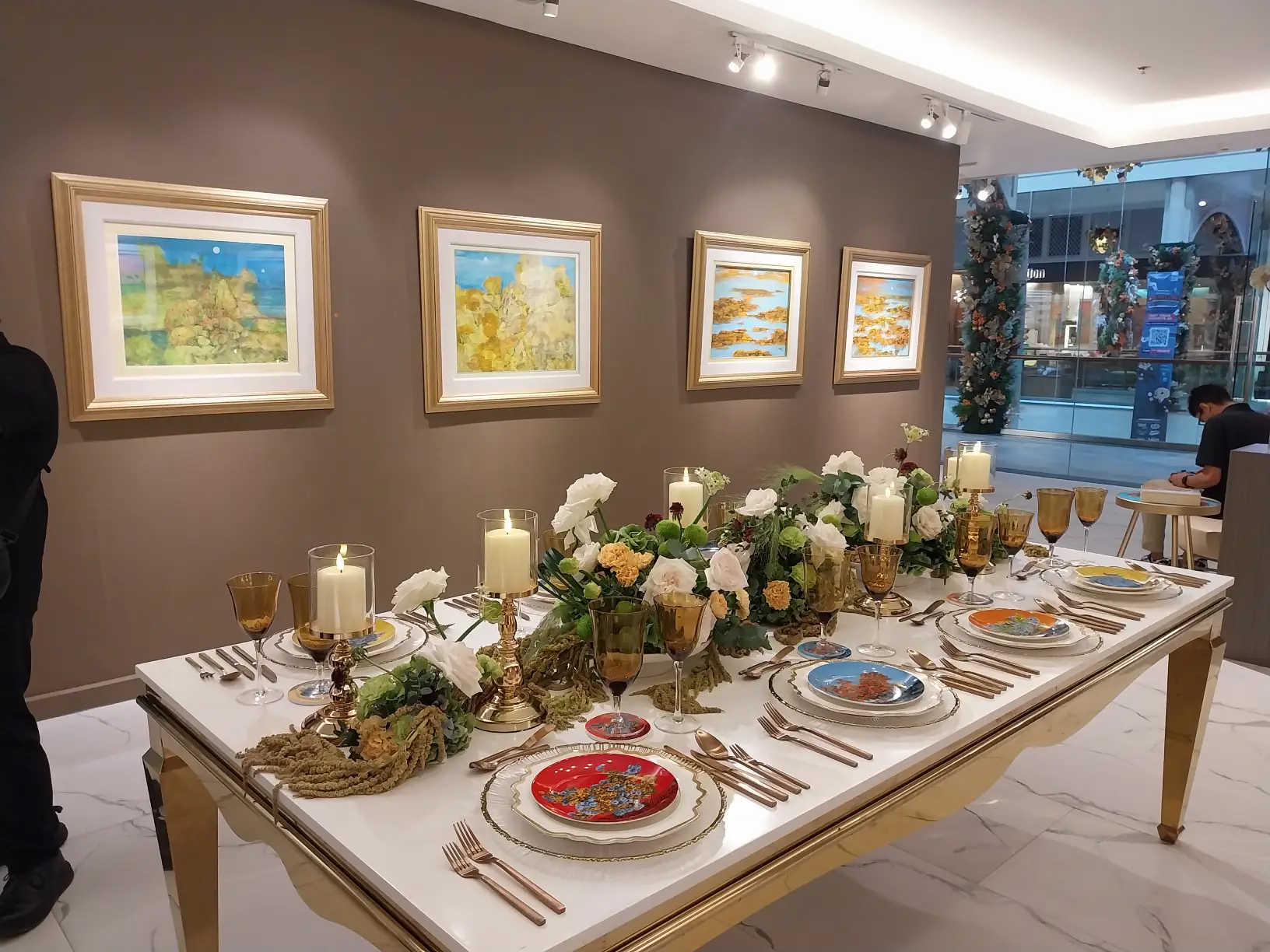 A dining room table with 'Casa Juan x Sansó' products set up with some of the works by Sanso on the walls.